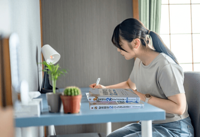 女性がテキスト「秘書検定2級クイックマスター」と「秘書検定2級パーフェクトマスター」を使って勉強している画像